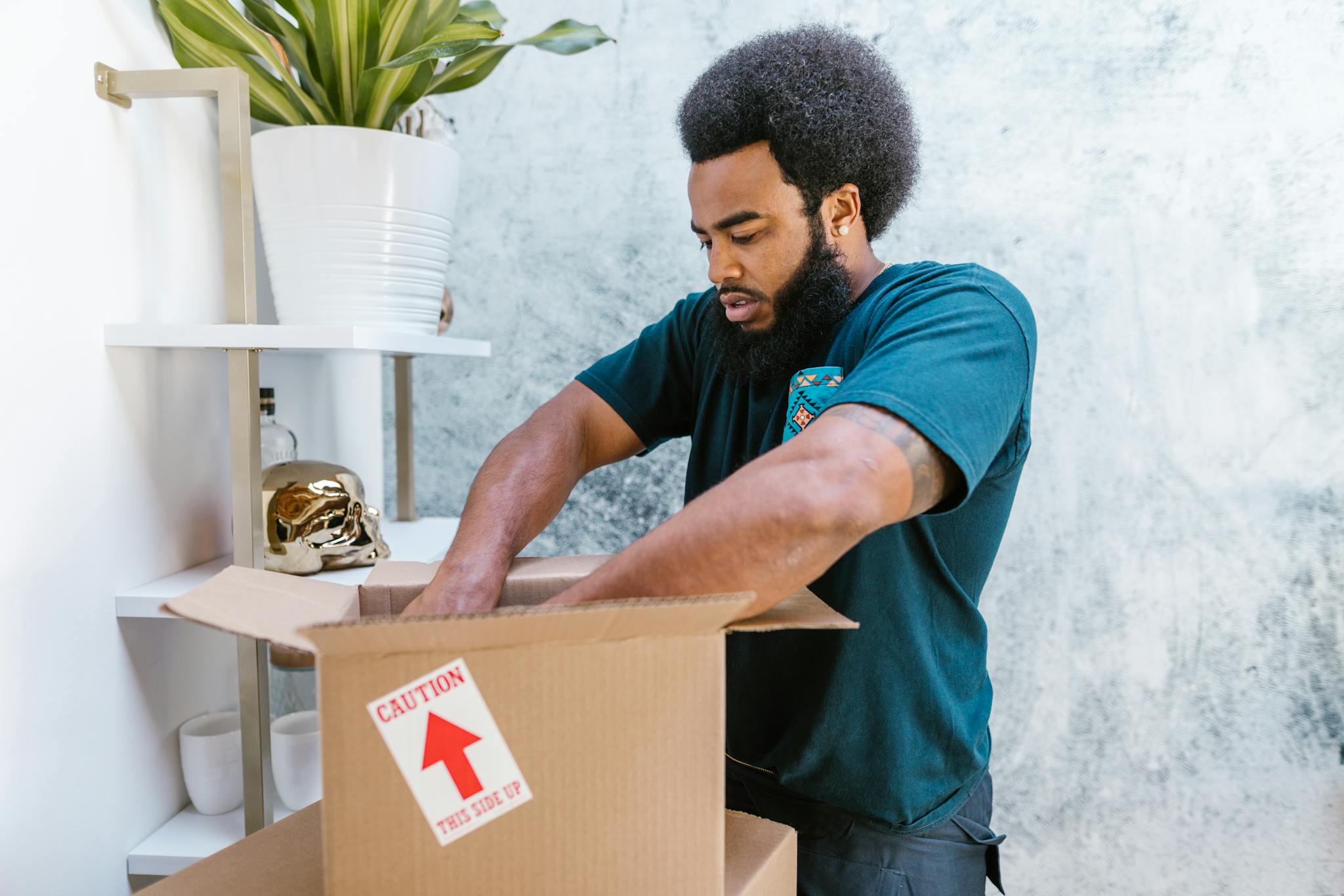 A professional mover packs a fragile item into a box in a stylish room.